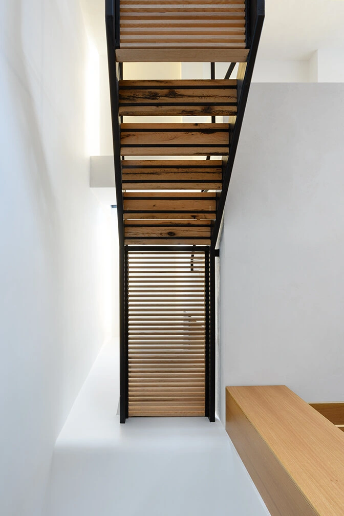 Underside of open wood stair treads against white walls in Williamsburg