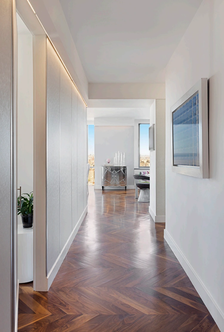 Upper West Side hallway in New York with herringbone wood flooring, white wall panels and concealed ceiling lighting