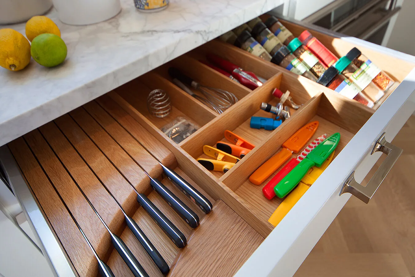 Kitchen utensil drawer with fitted wood dividers beneath a veined countertop on the Upper East Side