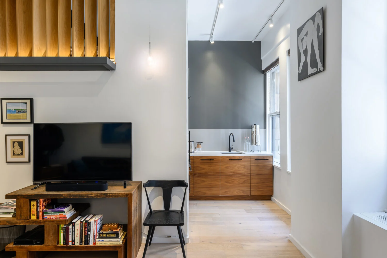 View from the Lexington living room toward a kitchen with wood cabinets and a gray accent wall in New York City