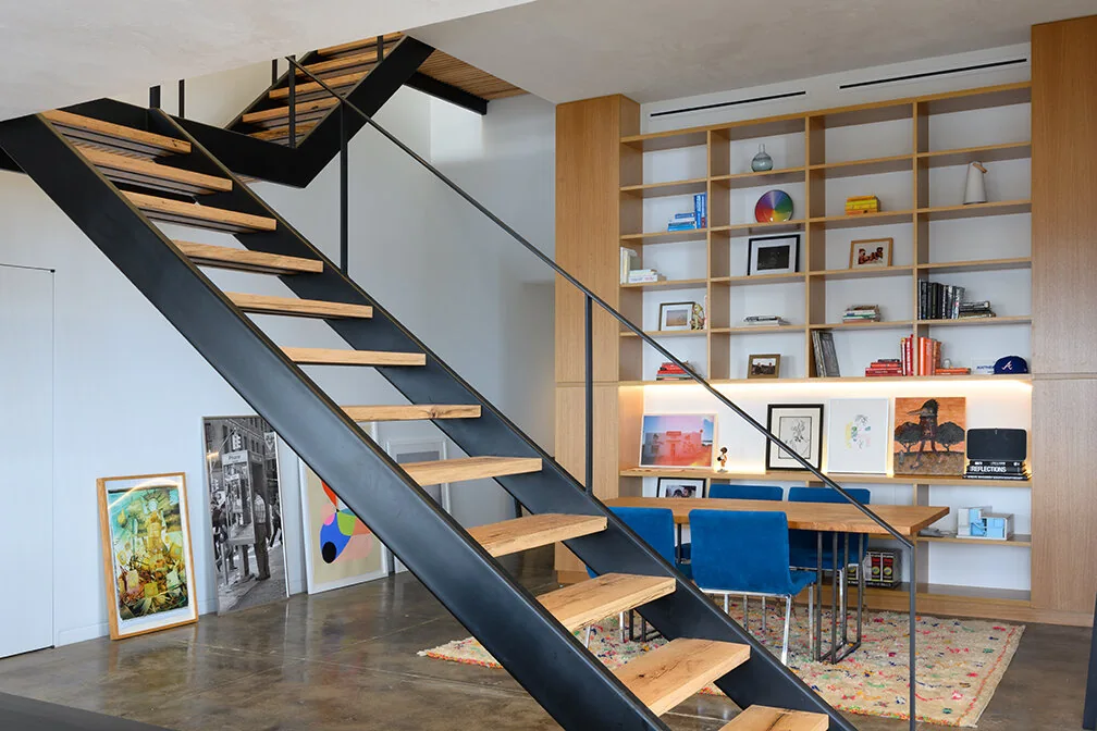Wood stair treads in a black frame beside built-in shelving in Williamsburg