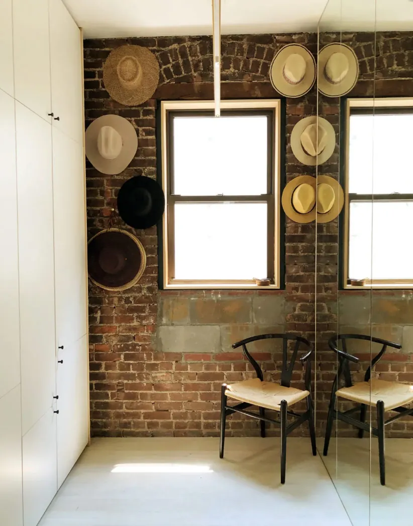 Exposed brick wall with a full height mirror and white storage cabinetry in a renovated NoHo apartment