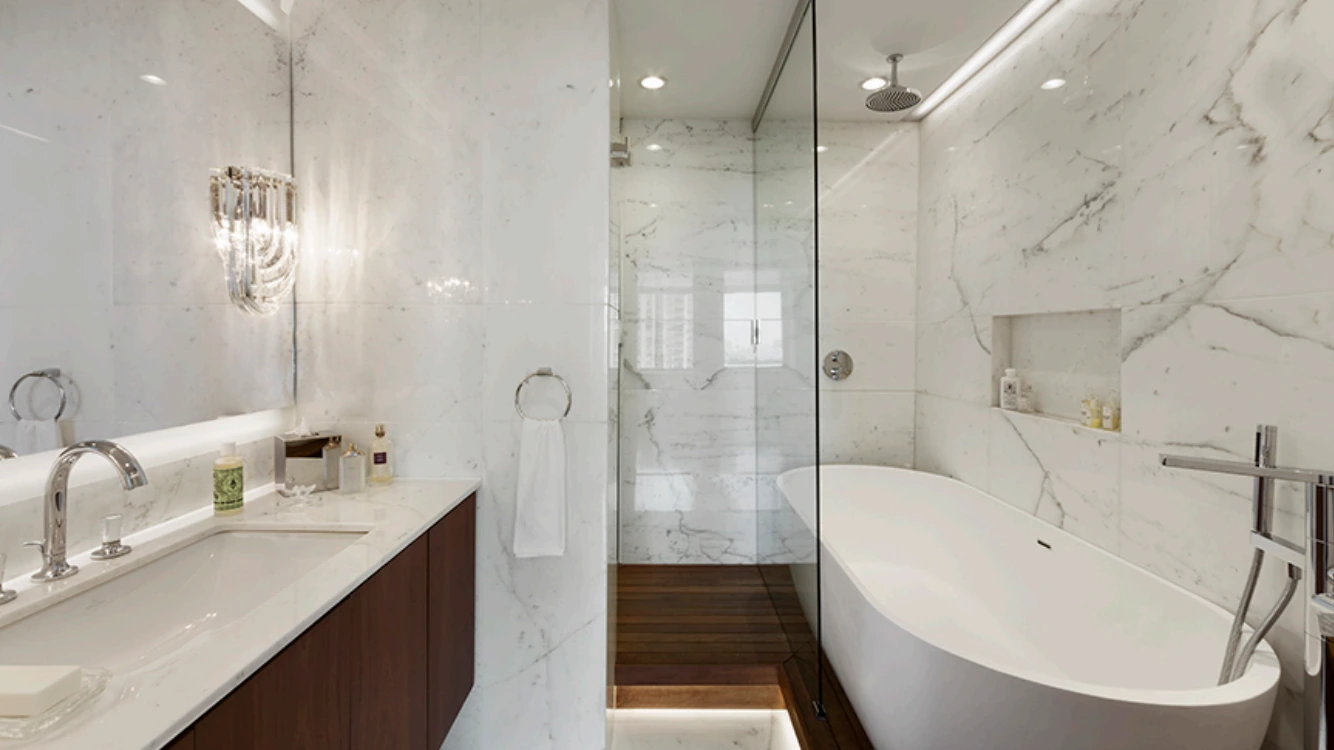 Upper West Side bathroom in New York with veined wall tiles, a wood vanity, glass shower and freestanding bathtub
