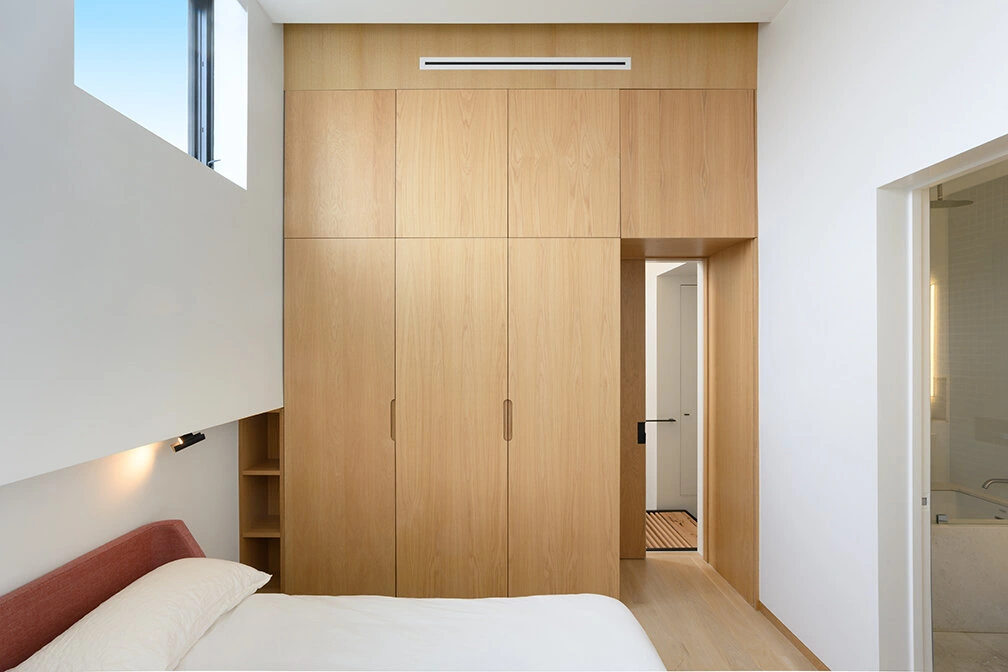 Full-height wood wardrobe cabinetry beside a bed in Williamsburg