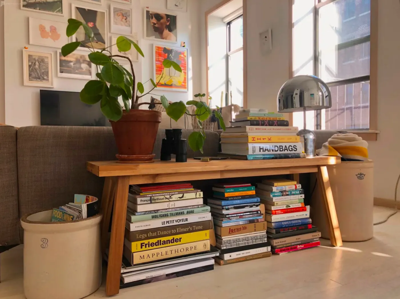 Wooden bench styled with art books and a potted plant in a renovated NoHo apartment
