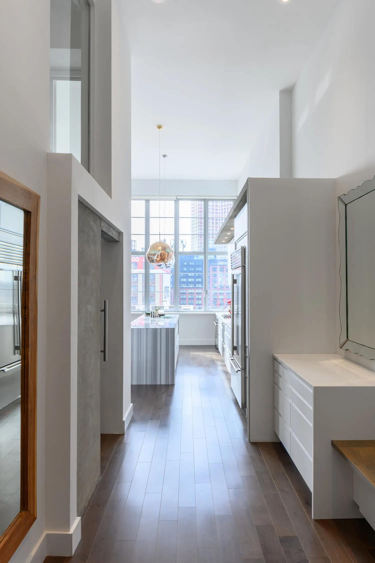 Finished Arris Lofts II entry hallway in Long Island City with wood flooring, tall glazed panels and built-in white storage