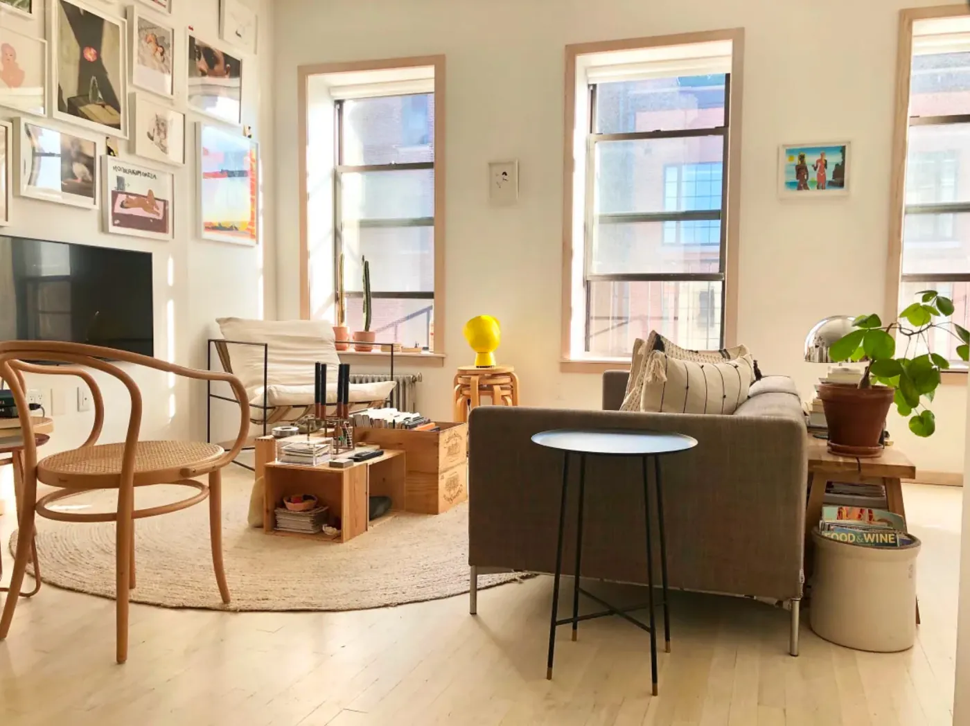 Living room seating area with a braided rug and tall windows in a renovated NoHo apartment