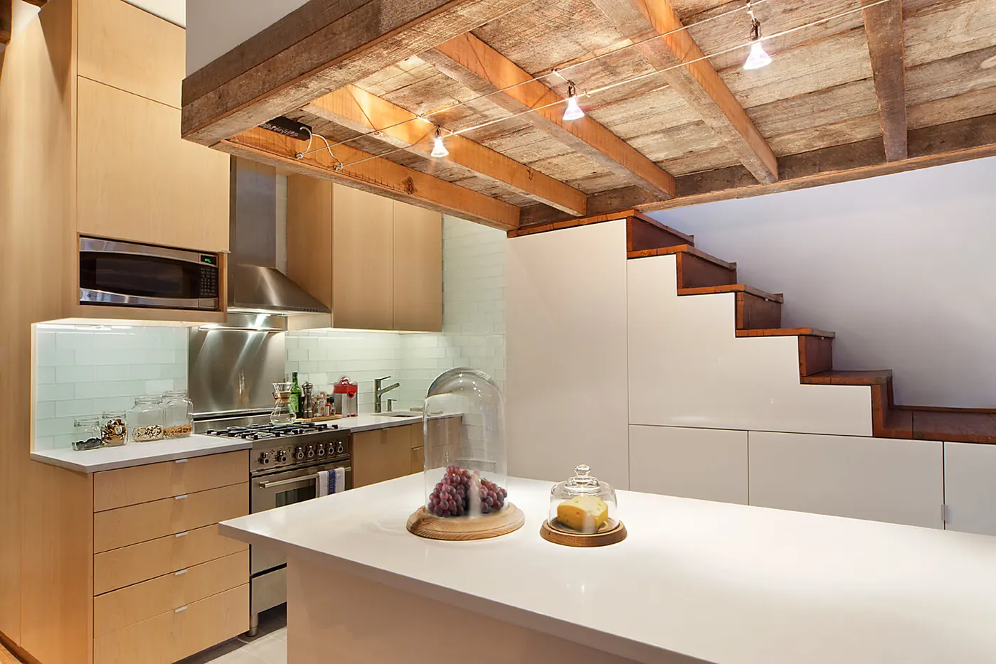 Kitchen in the Crane Residence with maple cabinetry, a corian countertop island and exposed reclaimed wood ceiling beams