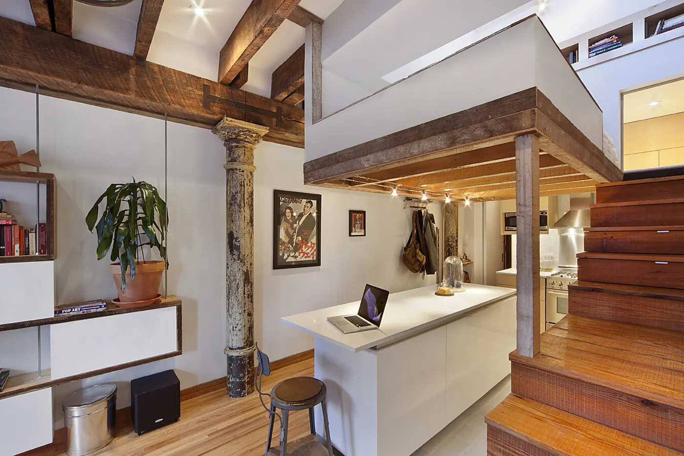 Open living space in the Crane Residence with exposed ceiling beams, a cast iron column and a staircase with built-in storage