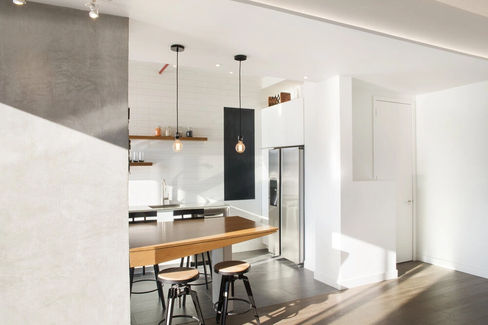 Open CityLights kitchen in Long Island City with a breakfast counter, refrigerator and sunlight across the adjoining floor