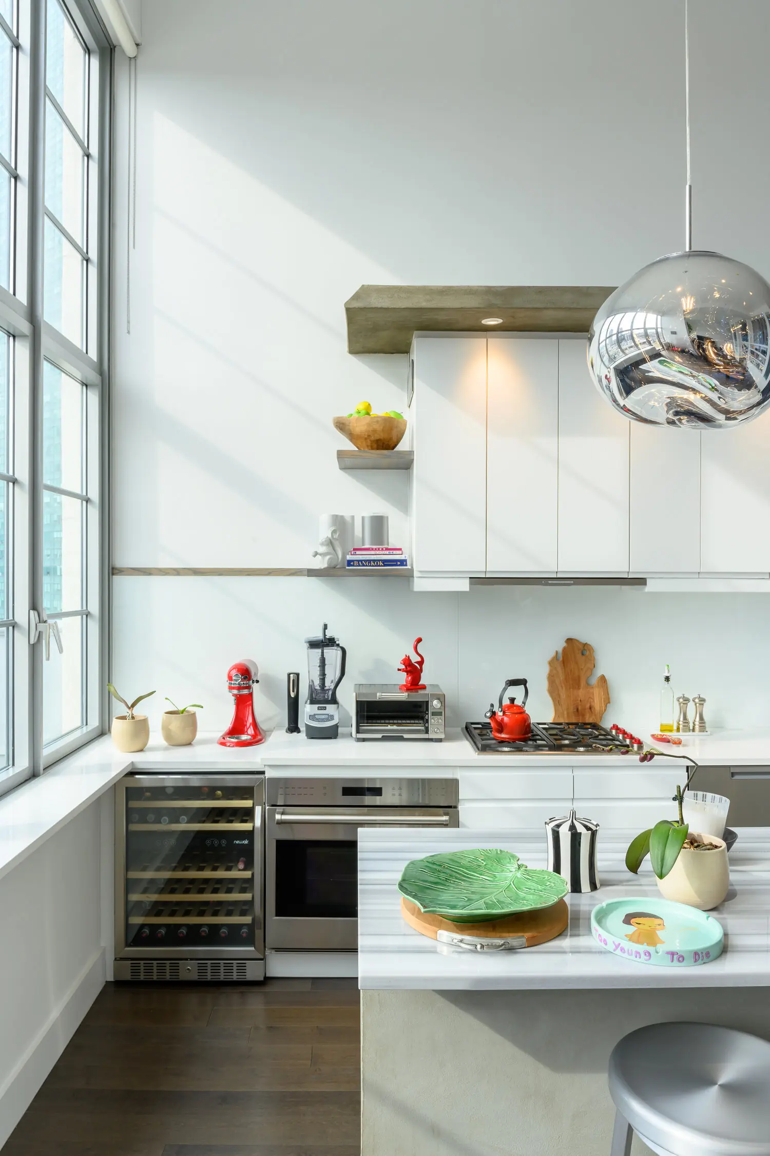 Arris Lofts II kitchen island beside a beverage cooler, white cabinets and a mirrored pendant in Long Island City, New York