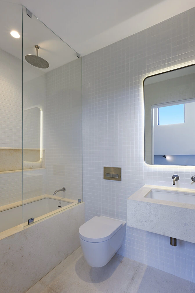 White tiled bathroom with a glass shower and compact fixtures in Williamsburg