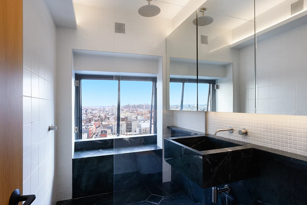 Glass shower and dark vanity beneath a wide bathroom mirror in Williamsburg