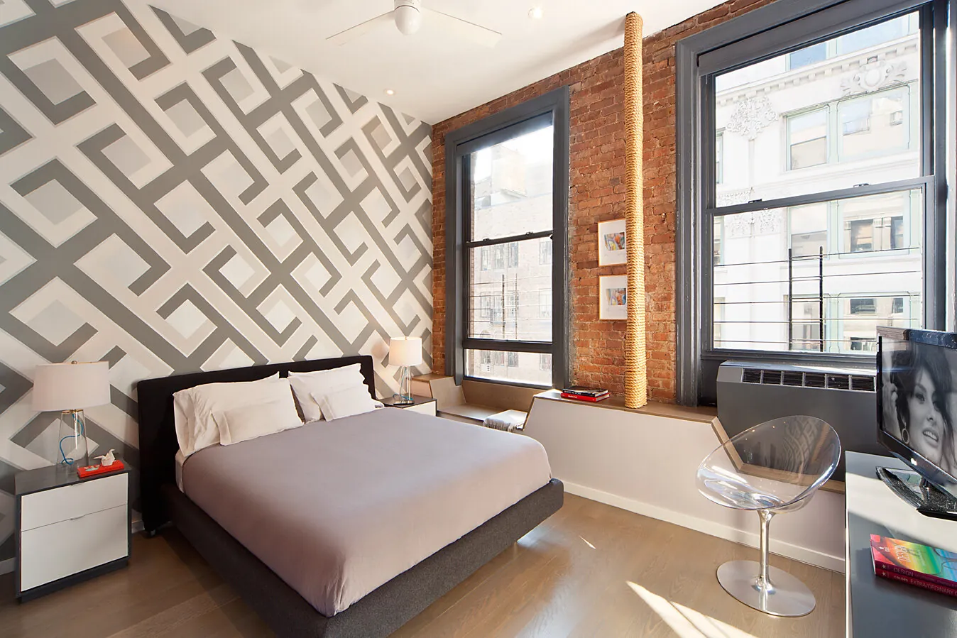 Bedroom in a Greenwich Village renovation with geometric wallpaper, exposed brick and large windows