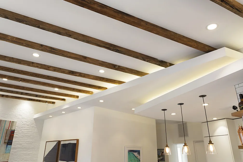 Exposed reclaimed wood ceiling beams with recessed lighting in a Greenwich Village apartment renovation