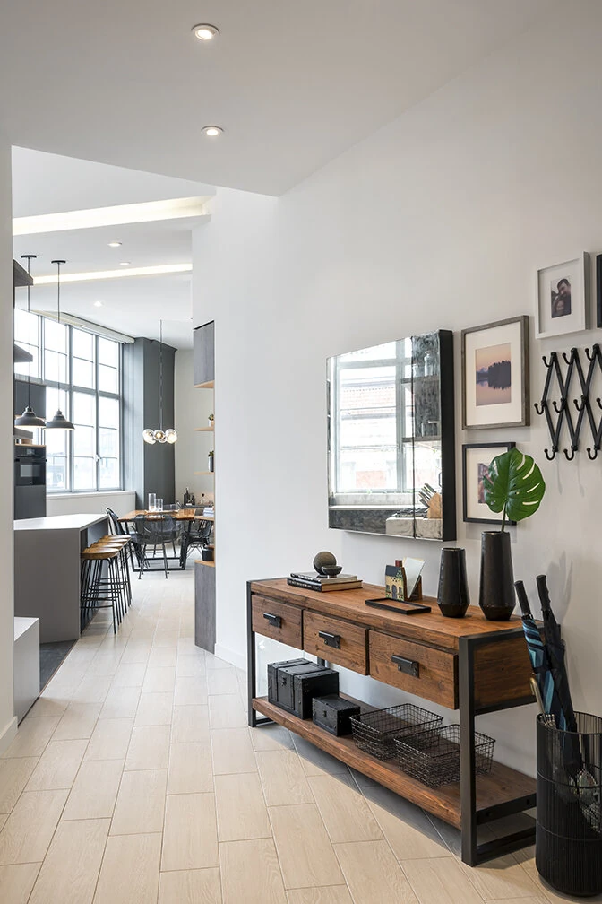 Light plank flooring through the Arris Lofts entry in New York, with a wood console and a view into the kitchen