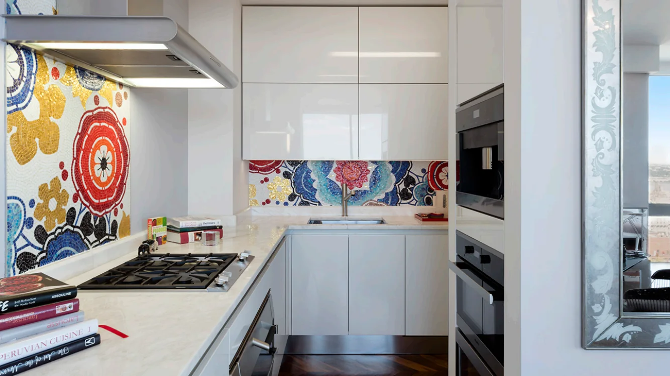 Upper West Side kitchen in New York with glossy white cabinets, colorful floral mosaic backsplash and fitted appliances