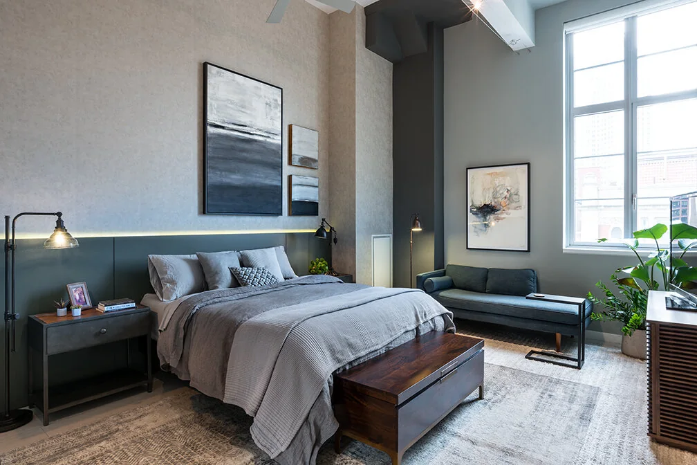 Arris Lofts bedroom in New York with textured walls, a tall window, bedside lighting and a window seat