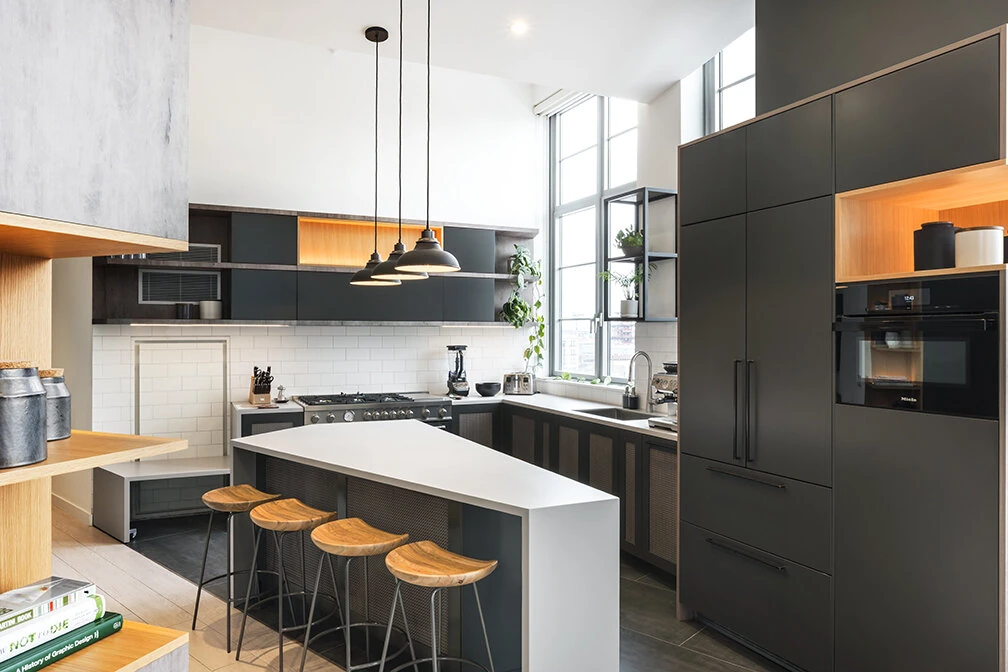 Arris Lofts kitchen in New York with dark cabinetry, a white island, wood stools and a white tile backsplash