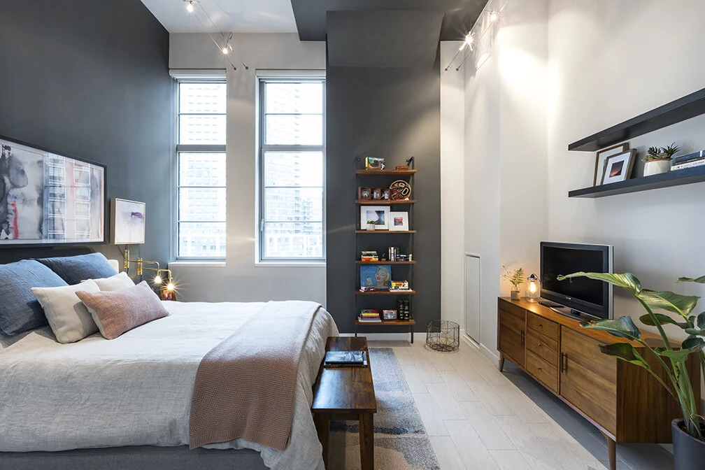 Finished bedroom at Arris Lofts in New York with contrasting walls, open shelving and a wood storage cabinet