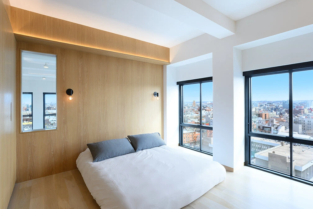 Bedroom with wood-lined walls and large windows in a Williamsburg loft
