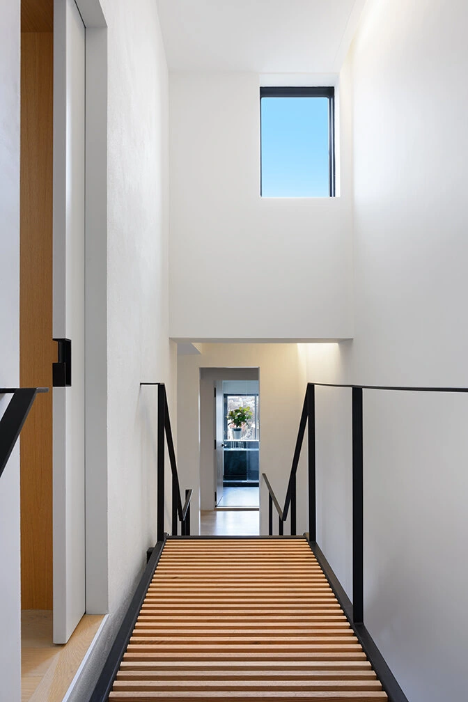Upper stair landing with black railings and a high window in Williamsburg