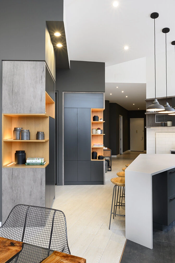 Tall dark cabinets and illuminated wood display shelves beside the kitchen island at Arris Lofts in New York