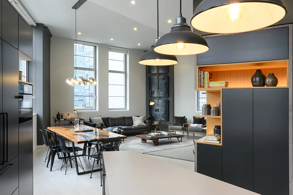 View from the Arris Lofts kitchen island in New York toward the dining table and living room beneath pendant lights