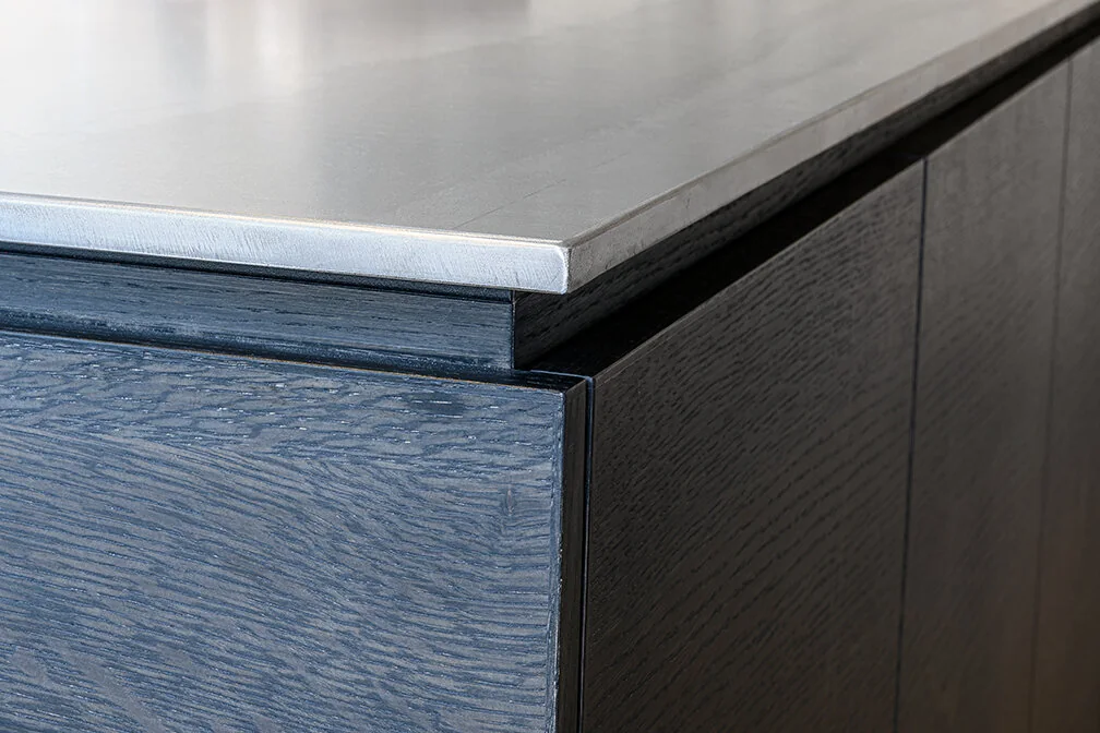 Close-up of dark wood kitchen cabinetry meeting a metal countertop in Williamsburg
