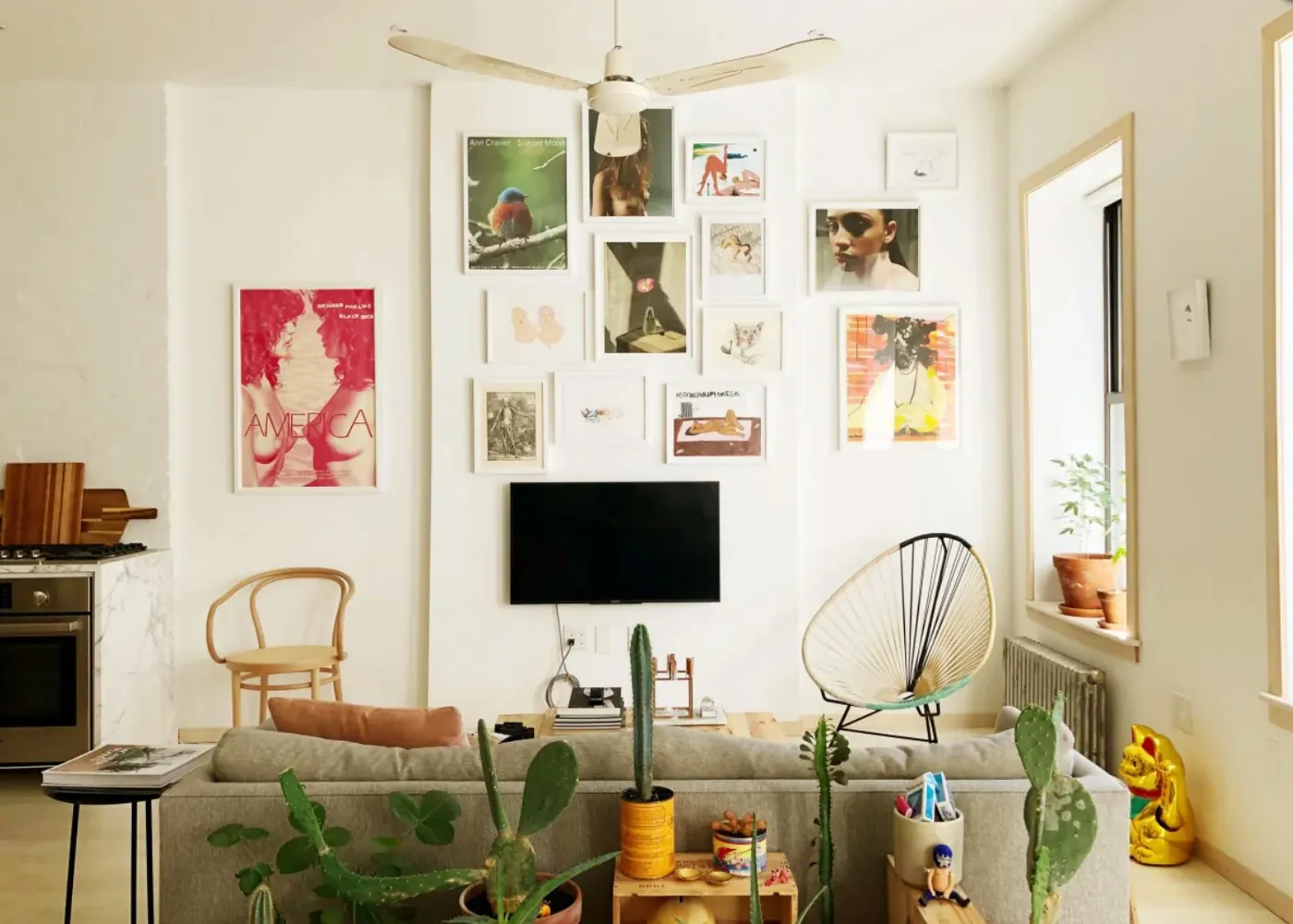 Living room with a gallery wall above the television and a glimpse of the marble kitchen counter in a renovated NoHo apartment
