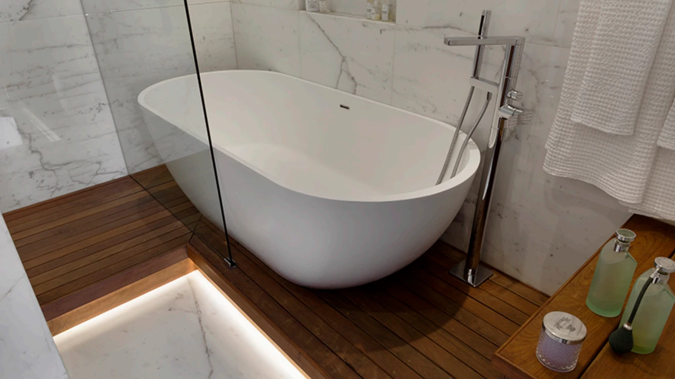 Freestanding white bathtub on a raised wood platform beside a glass shower in an Upper West Side bathroom