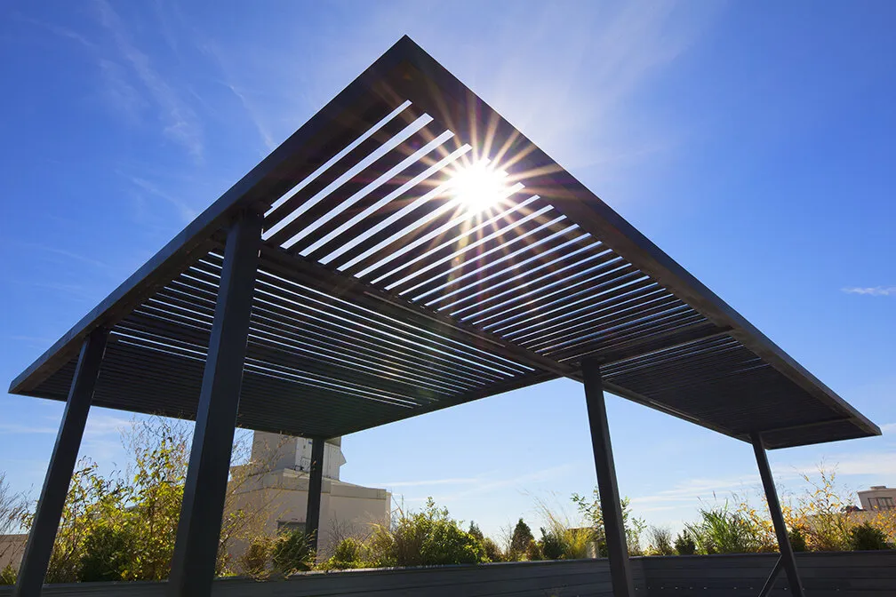 Sunlight filtering through the slatted roof of a custom steel pergola built by MELDNYC